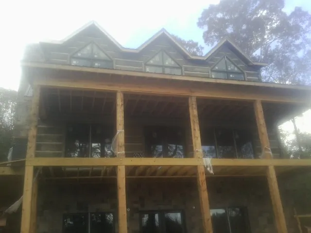 Dormers and porch framing on a large log home under construction — Roof Coating work by our crew in Portage