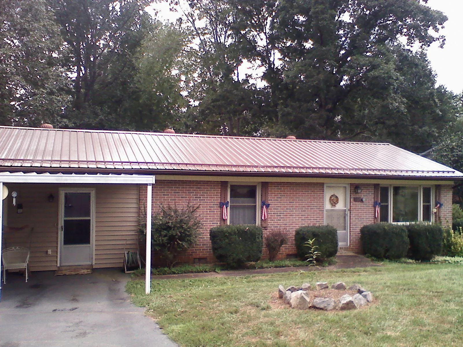 Bronze metal roof and carport on a brick ranch home — Roof Repair work by our crew in Portage